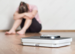 a sad woman sitting by her scale